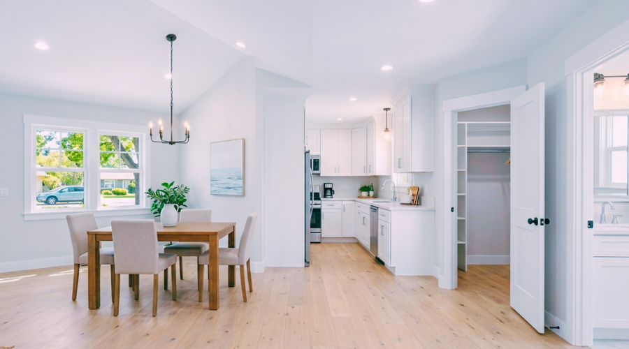 An immaculate, decluttered modern home interior showcasing a spotless white kitchen with clear counters, an organized open closet, and a pristine bathroom vanity with updated lighting, creating an open and bright showing experience.