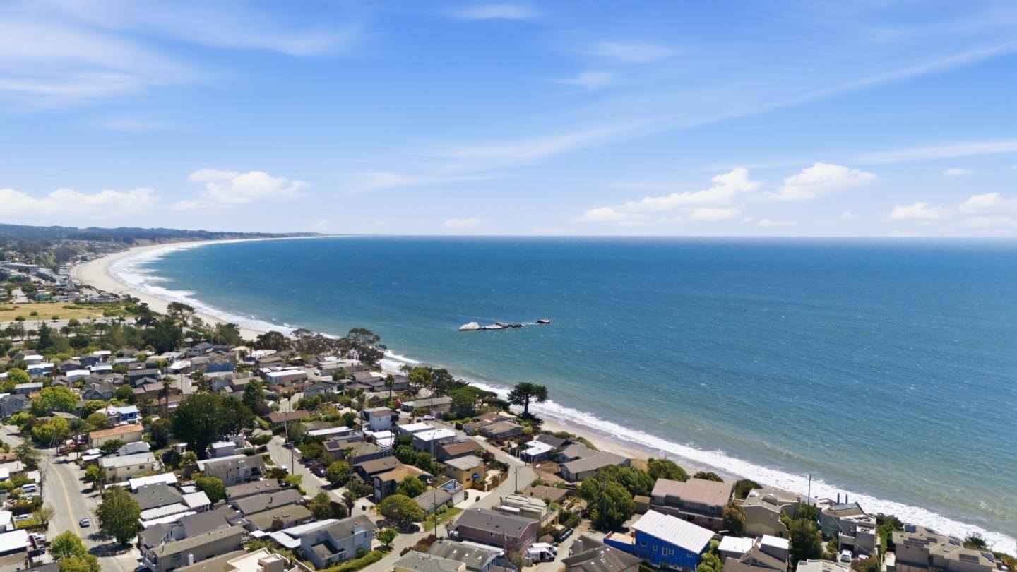 Santa Cruz Coastal Homes With Ocean View and Beach Access Aerial view of Santa Cruz coastal homes near the beach with a wide ocean view, shoreline, neighborhood streets, and nearby houses, showing the coastal setting and location appeal that can influence buyer activity, offer strength, and home-selling strategy in the Santa Cruz market.