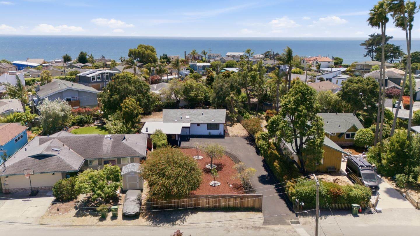 Santa Cruz Ocean View Home Near Coastal Neighborhood Aerial view of a Santa Cruz single-family home in a coastal neighborhood with ocean views, mature landscaping, nearby homes, driveway space, and beach proximity, showing the location features and buyer appeal that can affect first-offer strength and home-selling strategy in Santa Cruz County.