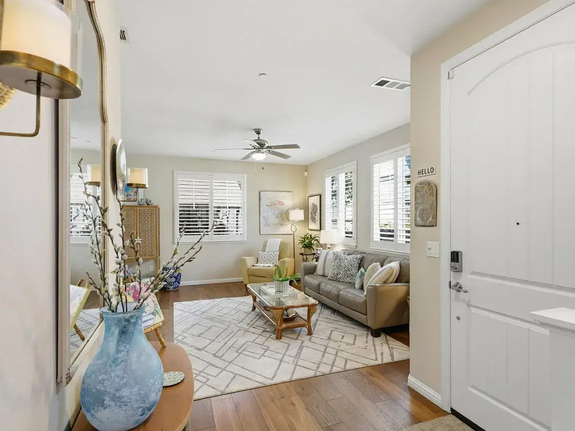 Staged Santa Cruz Entryway and Living Room Before Listing Bright staged entryway and living room in a Santa Cruz home featuring a white front door, hardwood floors, neutral furniture, area rug, plantation shutters, natural light, and clean move-in ready styling. This image highlights how thoughtful presentation and interior staging can help Santa Cruz properties show well during the home selling timeline from listing preparation to buyer showings.