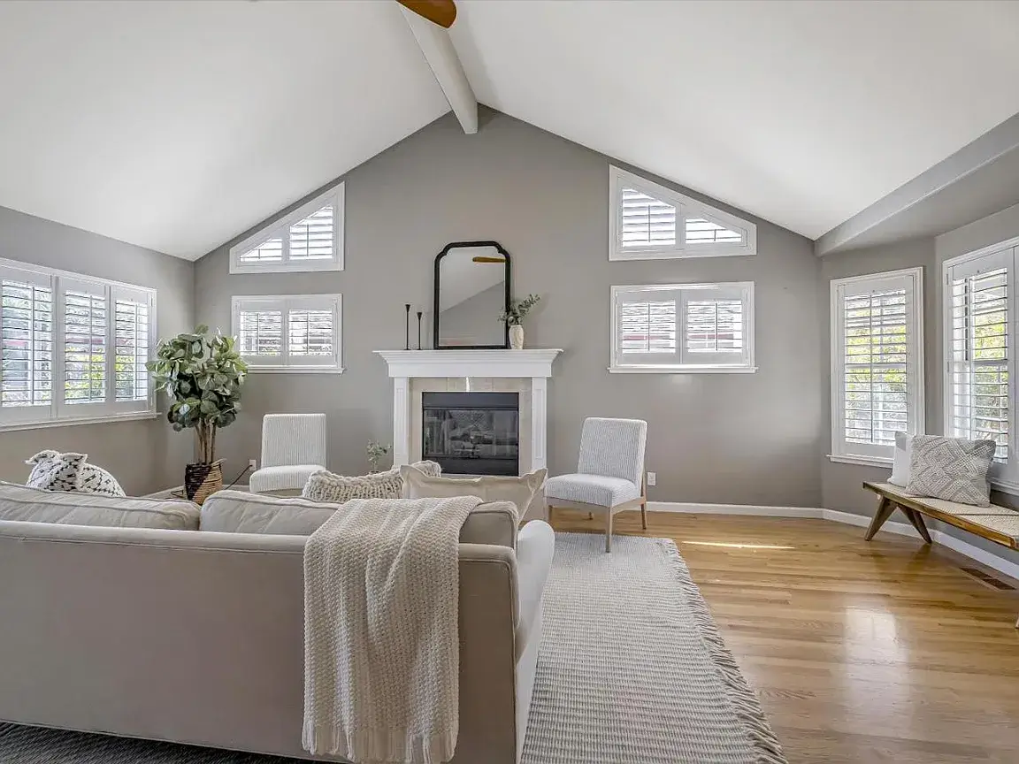 Staged Santa Cruz Living Room With Vaulted Ceiling and Fireplace Bright staged living room in a Santa Cruz home featuring vaulted ceilings, hardwood floors, white plantation shutters, a fireplace, neutral furniture, soft natural light, and clean move-in ready styling. This image highlights interior presentation for Santa Cruz properties and shows how staging, natural light, and updated finishes can help houses for sale in Santa Cruz appeal to buyers quickly.